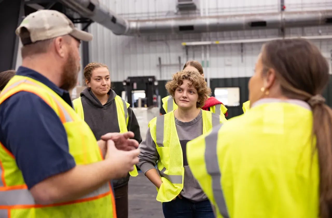 A Smith student looks interested during a tour of Vanguard Renewables, where the entire group wears bright yellow vests