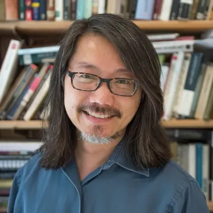 Floyd Cheung in front of a bookshelf.